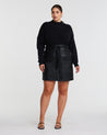 A plus-size fashionista wearing a Black PU Vegan Leather Belted Skirt.