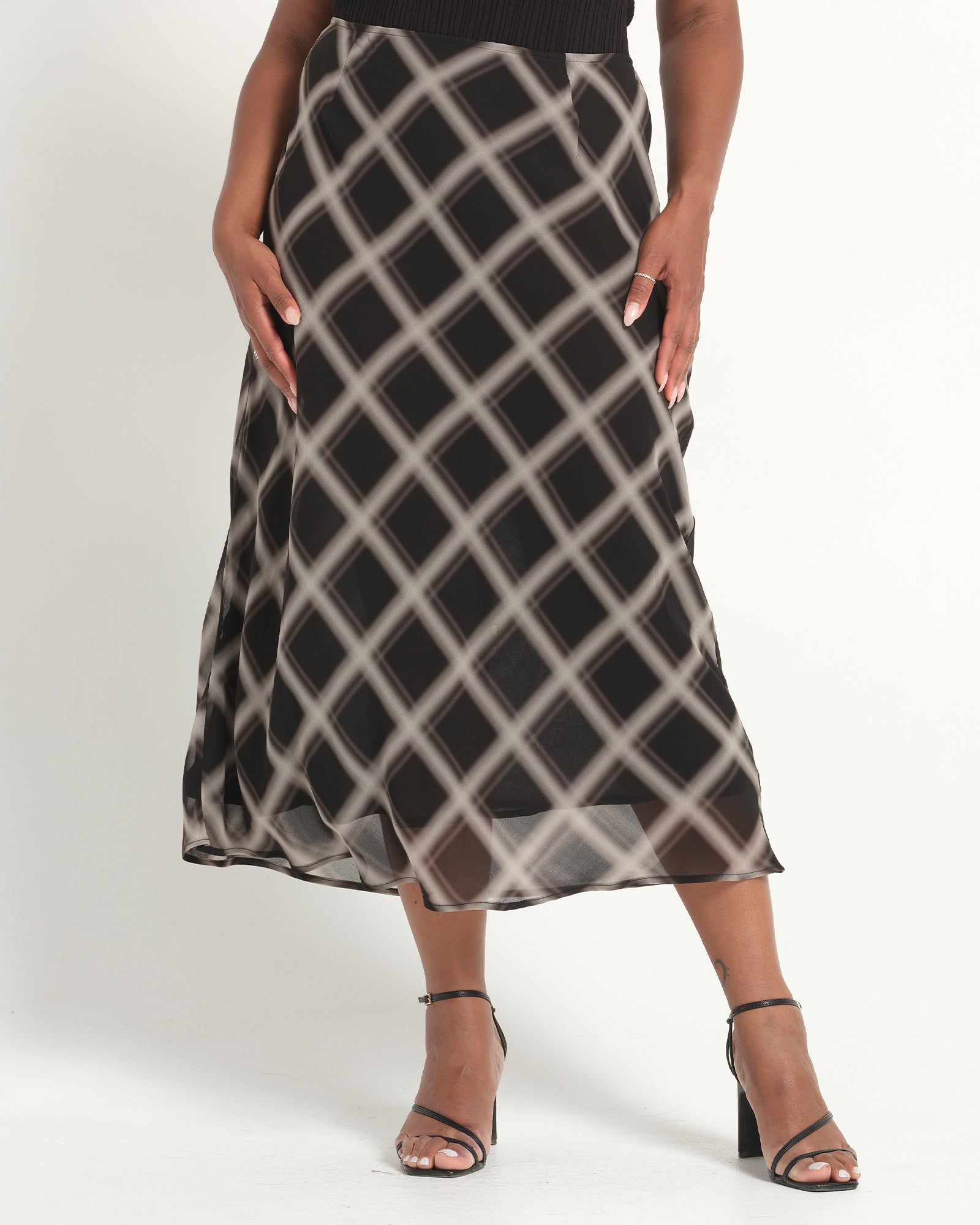 Person wearing a black and gray checkered skirt on a white background