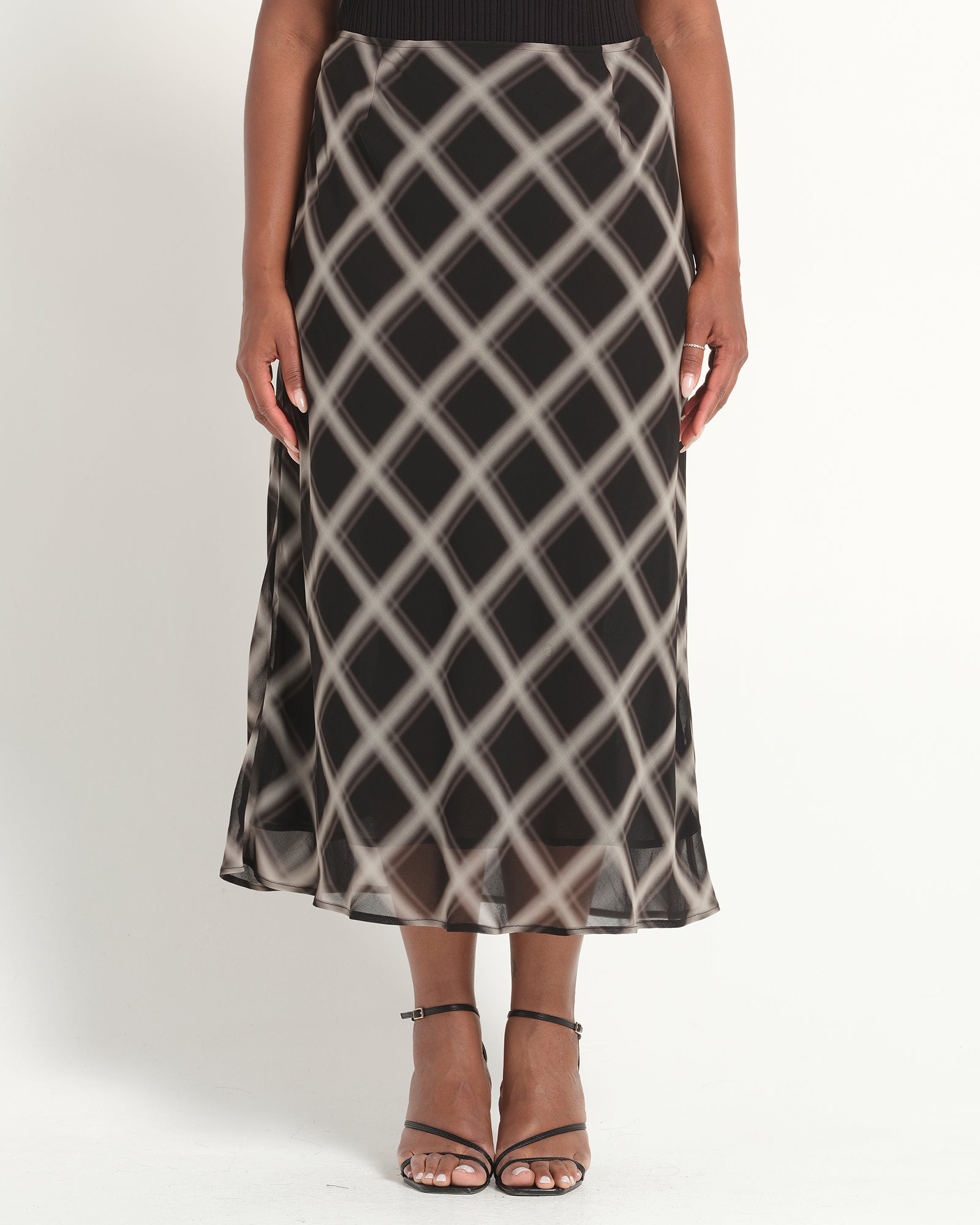 Person wearing a black and white patterned skirt on a plain background