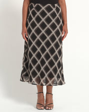 Person wearing a black and white patterned skirt on a plain background