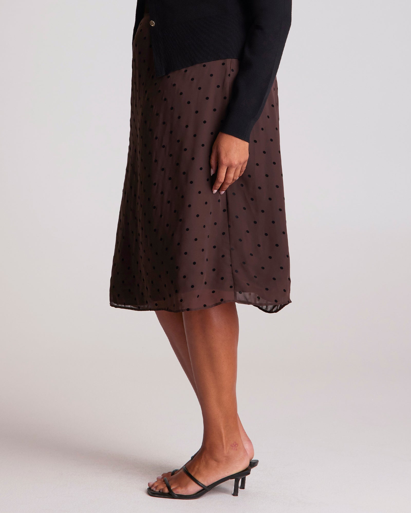 Brown polka dot skirt worn by a person on a white background