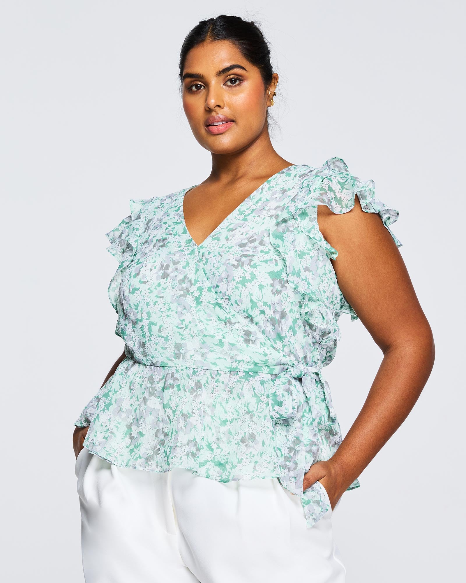 A plus size woman wearing white pants and an Estelle Green Prairie Top.