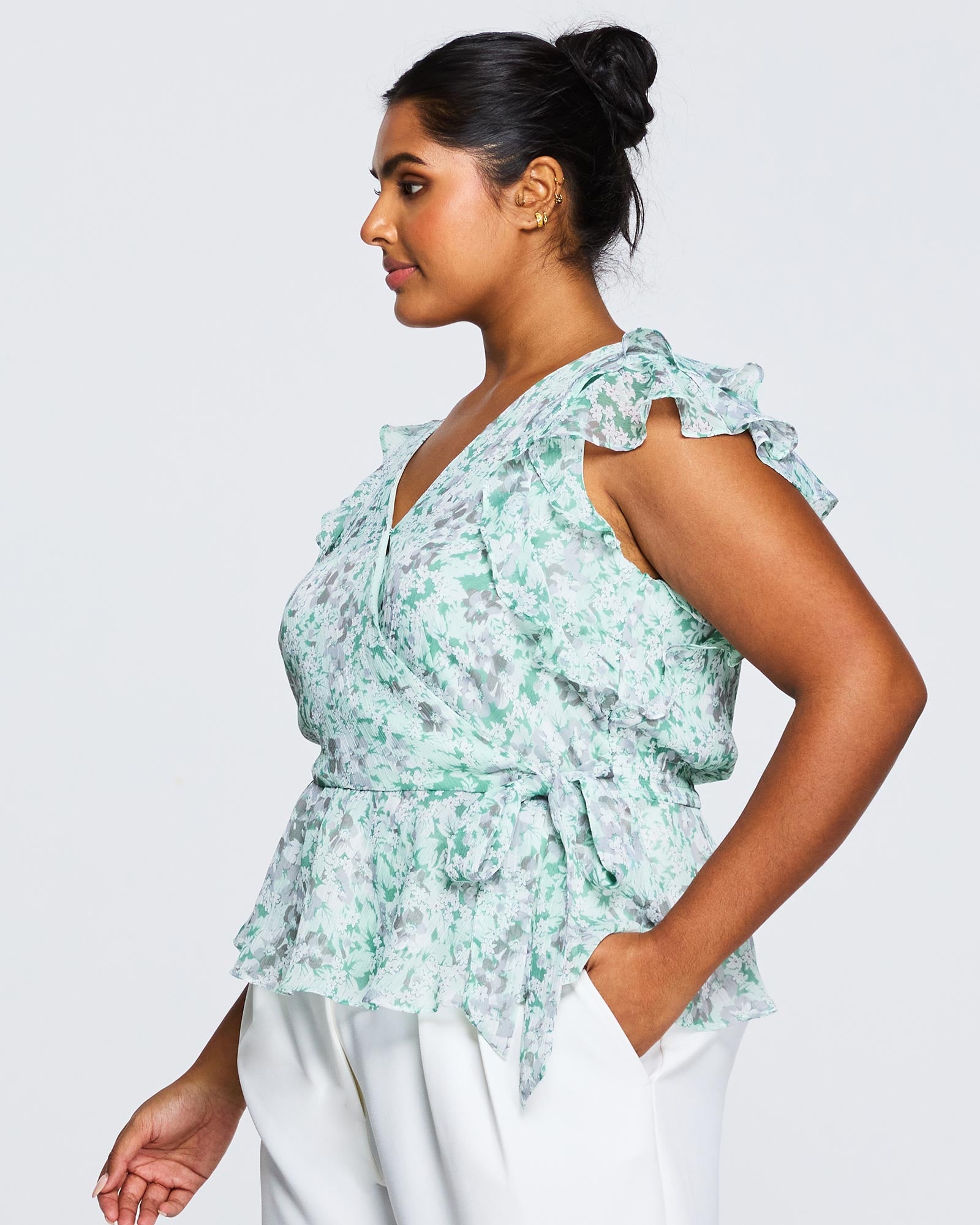 A plus size woman wearing white pants and an Estelle Green Prairie Top.