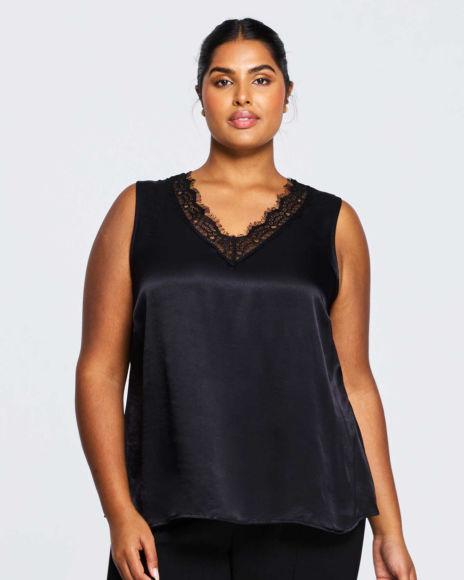 A plus size woman wearing an Alessandra Black Lace Satin Camisole Top and black pants from Estelle-us brand.