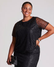 Woman wearing a black sequin dress against a plain background