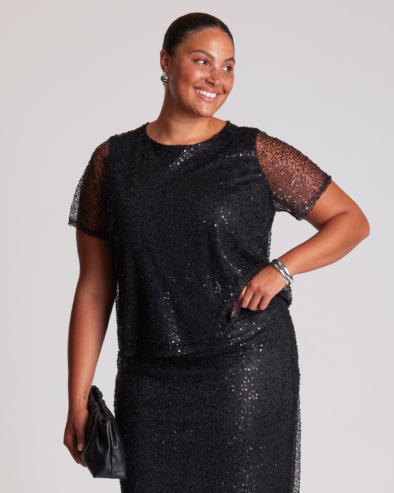 Woman wearing a black sequin dress against a plain background