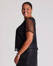 Woman wearing a black sequin dress against a plain background