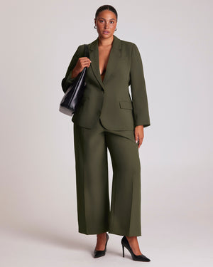 The Estelle Women's Olea Tailored Pant - Dark Green features a classic front fly opening, functional side pockets and back welt pockets for a clean, tailored appearance. Elasticated side waist panels provide added comfort while maintaining a polished silhouette, and the lined pocket bags create a considered finish. The wide-leg cut offers versatile styling options, making these women's wide-leg trousers an effortless choice for both professional and casual outfits.