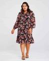 A plus-sized woman wearing a Woodland Floral Textured Mini Dress, creating an ideal addition to her transeasonal wardrobe.