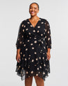 A plus-sized woman wearing a Black Polka Dot Midi Dress with 3/4 Sleeve.