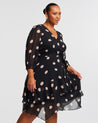 A plus-sized woman wearing a Black Polka Dot Midi Dress with 3/4 Sleeve.