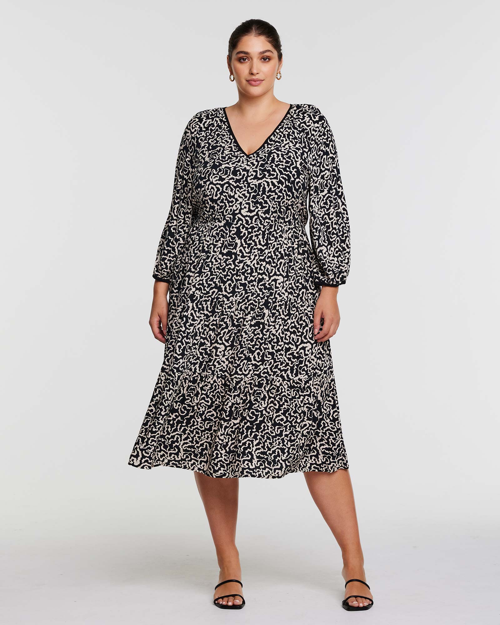 A plus size woman wearing an Estelle Sparrow Long Sleeve Black and Cream Midi Dress.