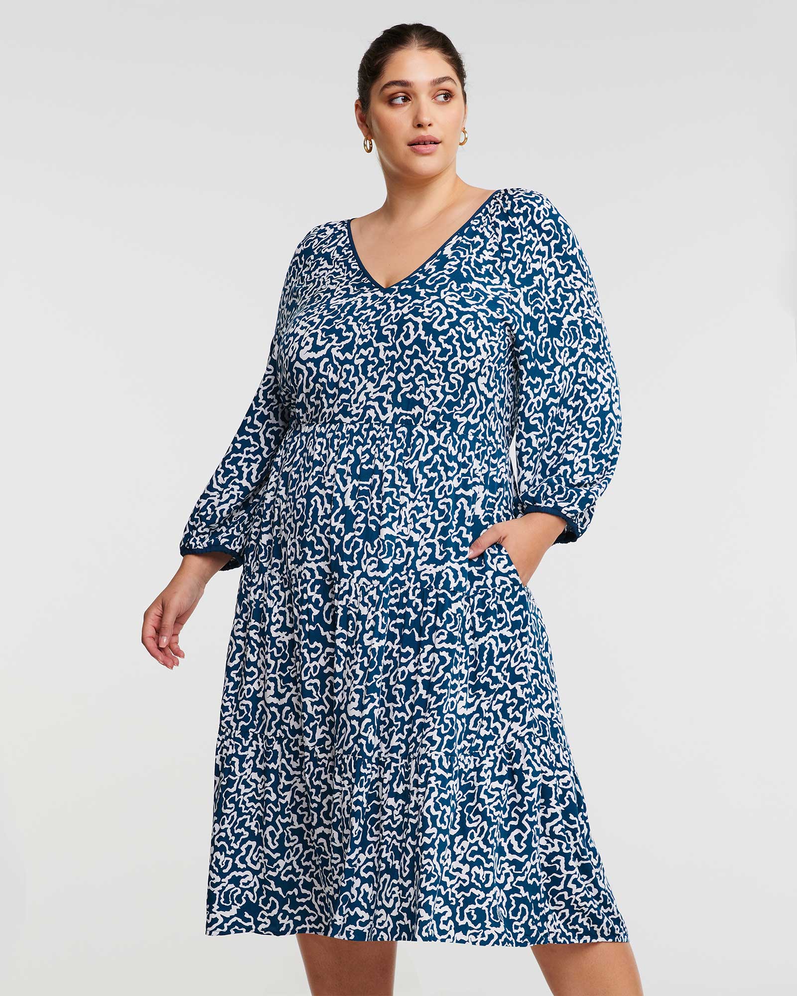 A plus size woman wearing an Estelle Sparrow Long Sleeve Teal and White Midi Dress.