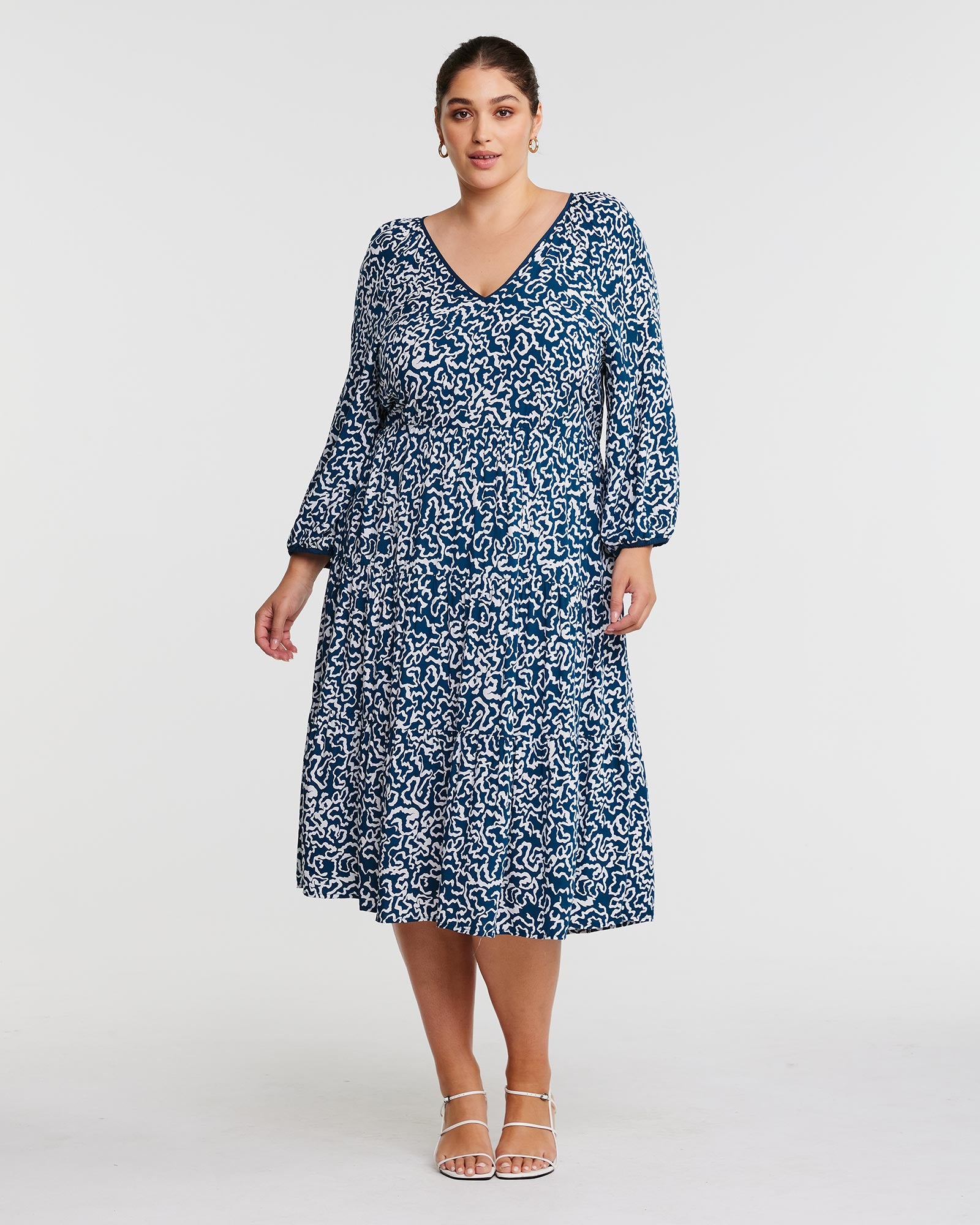 A woman wearing a Estelle Sparrow Long Sleeve Teal and White Midi Dress.