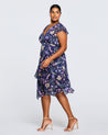 A plus size woman wearing the Estelle Botanical Purple Garden Knee Length Dress.