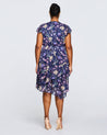 The back view of a plus size woman wearing the Estelle Botanical Purple Garden Knee Length Dress.