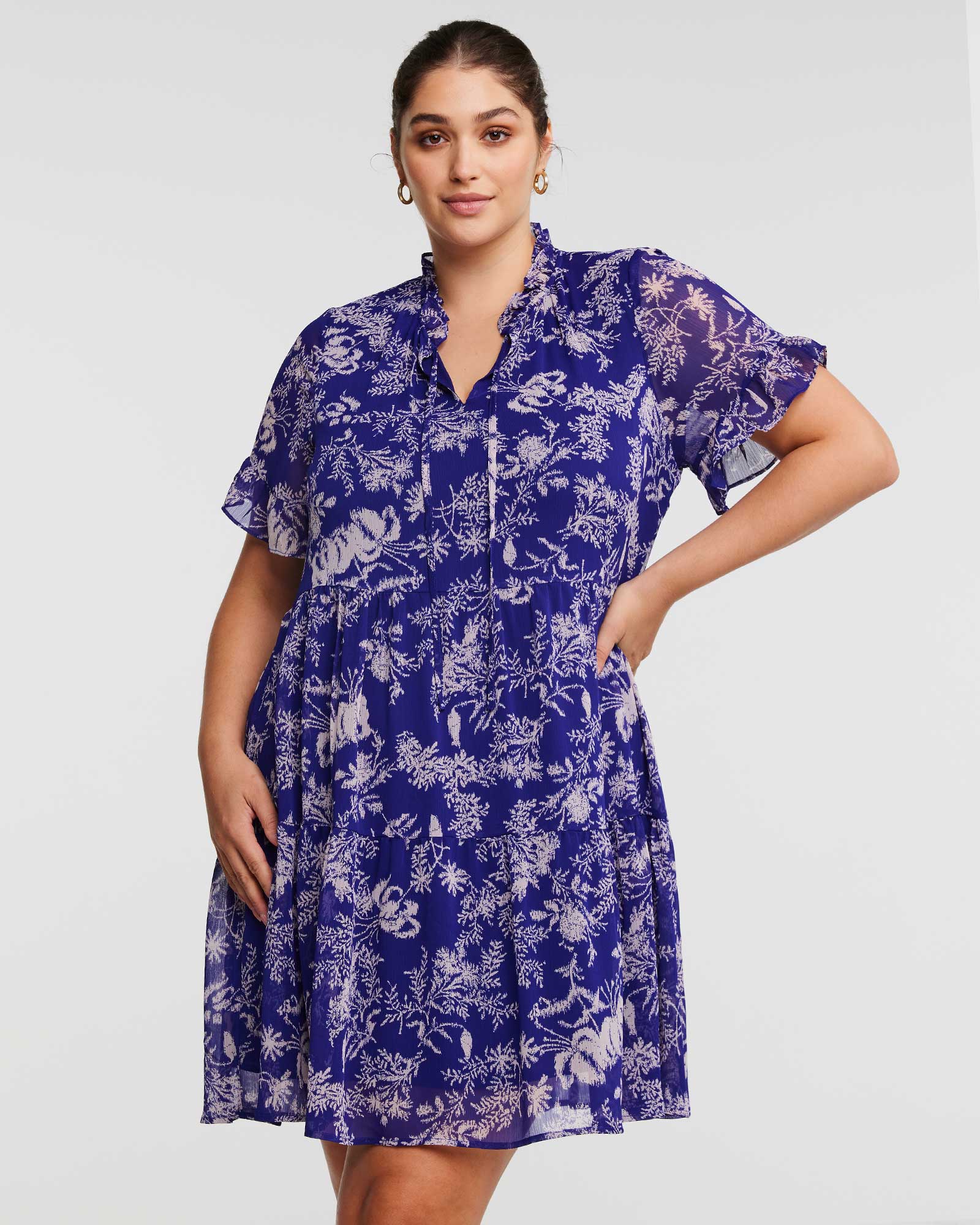 A plus size woman wearing an Estelle Ultra Leaf Purple Tiered Knee Length Dress.