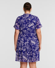 The back view of a woman wearing an Estelle Ultra Leaf Purple Tiered Knee Length Dress.