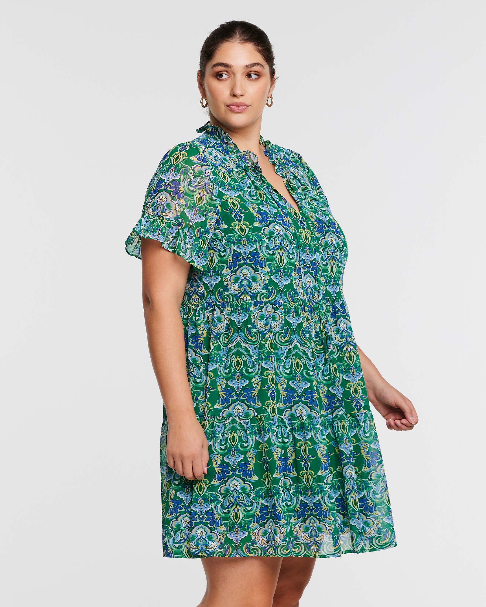 A plus size woman wearing the Estelle Mandala Green Tiered Mini Dress.