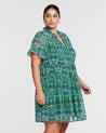 A plus size woman wearing the Estelle Mandala Green Tiered Mini Dress.