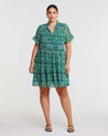 A plus size woman wearing an Estelle Mandala Green Tiered Mini Dress.