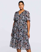 A plus size woman wearing an Estelle Maya Purple Paisley Midi Dress.