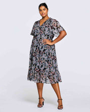 A plus size woman wearing an Estelle Maya Purple Paisley Midi Dress.