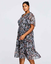 A plus size woman wearing the Estelle Maya Purple Paisley Midi Dress.