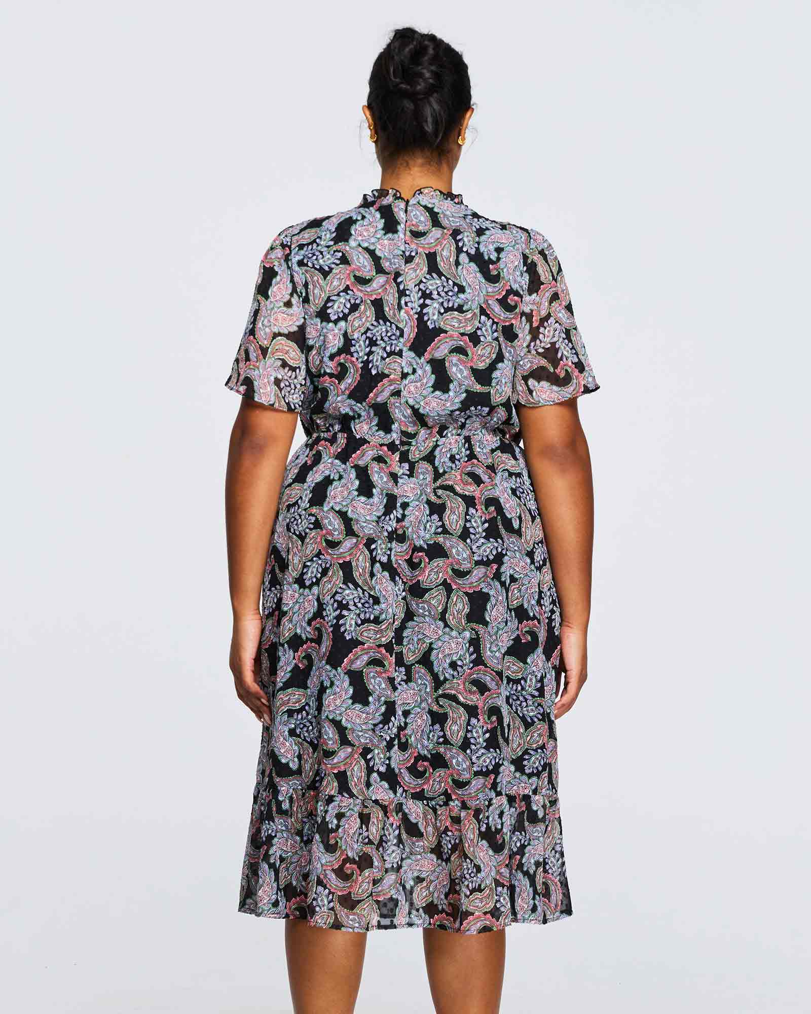 The back view of a plus size woman wearing a Estelle Maya Purple Paisley Midi Dress.