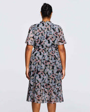The back view of a plus size woman wearing a Estelle Maya Purple Paisley Midi Dress.