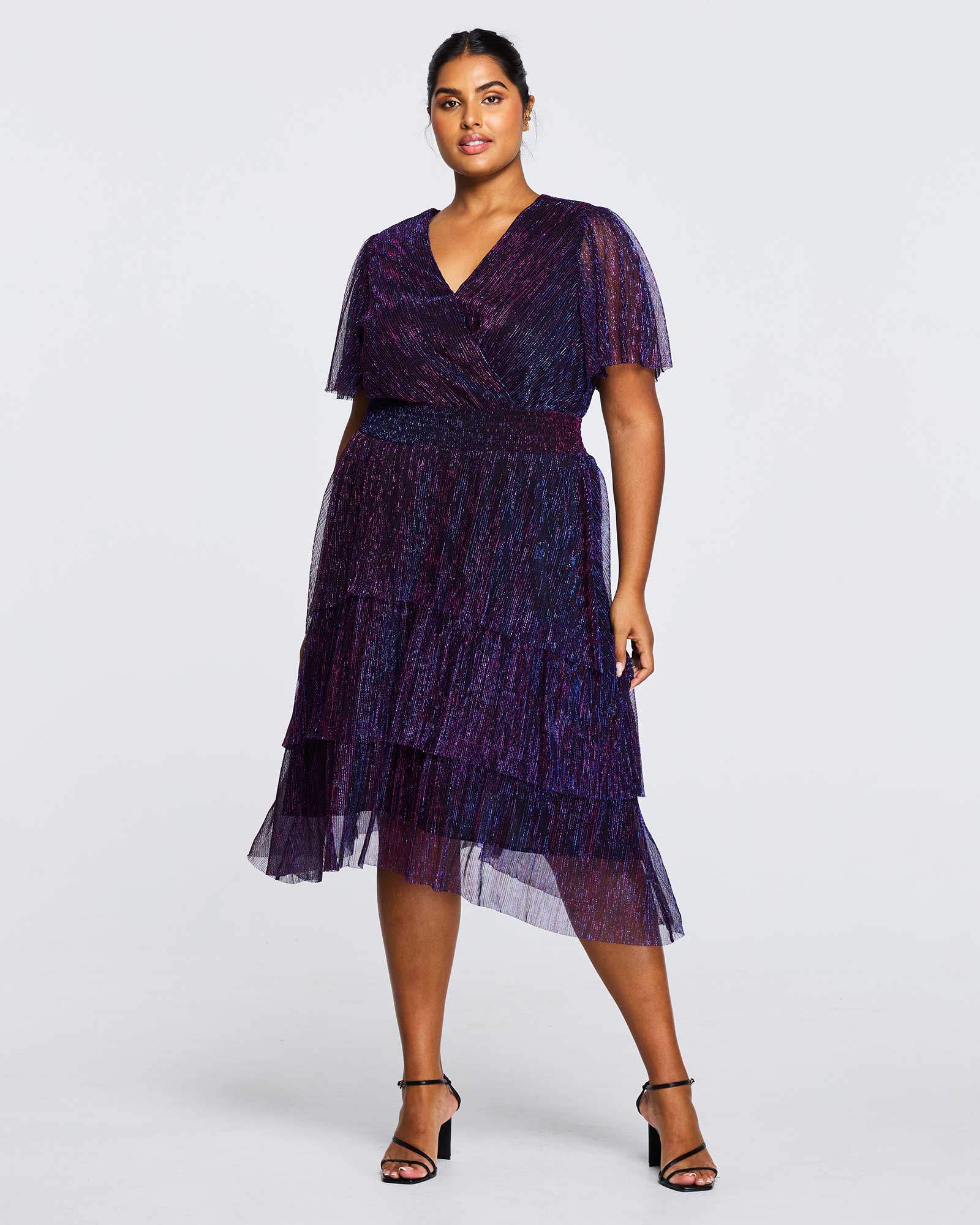 A plus size woman wearing the Glitterland metallic sparkly purple tulle midi dress.