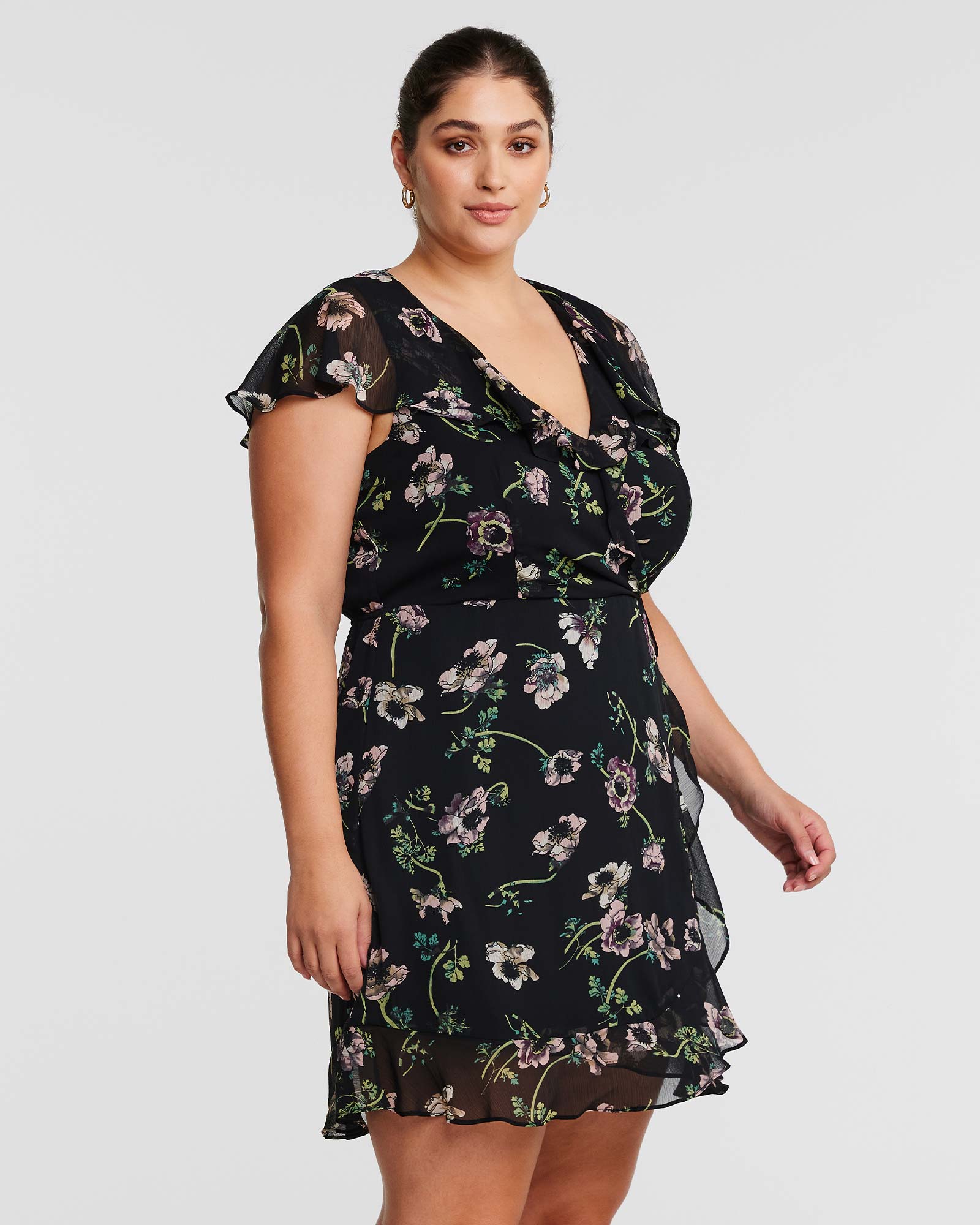 A plus size woman wearing an Estelle Climbing Rose Black Mini Dress.