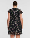 The back view of a woman in a Climbing Rose Black Mini Dress by Estelle.