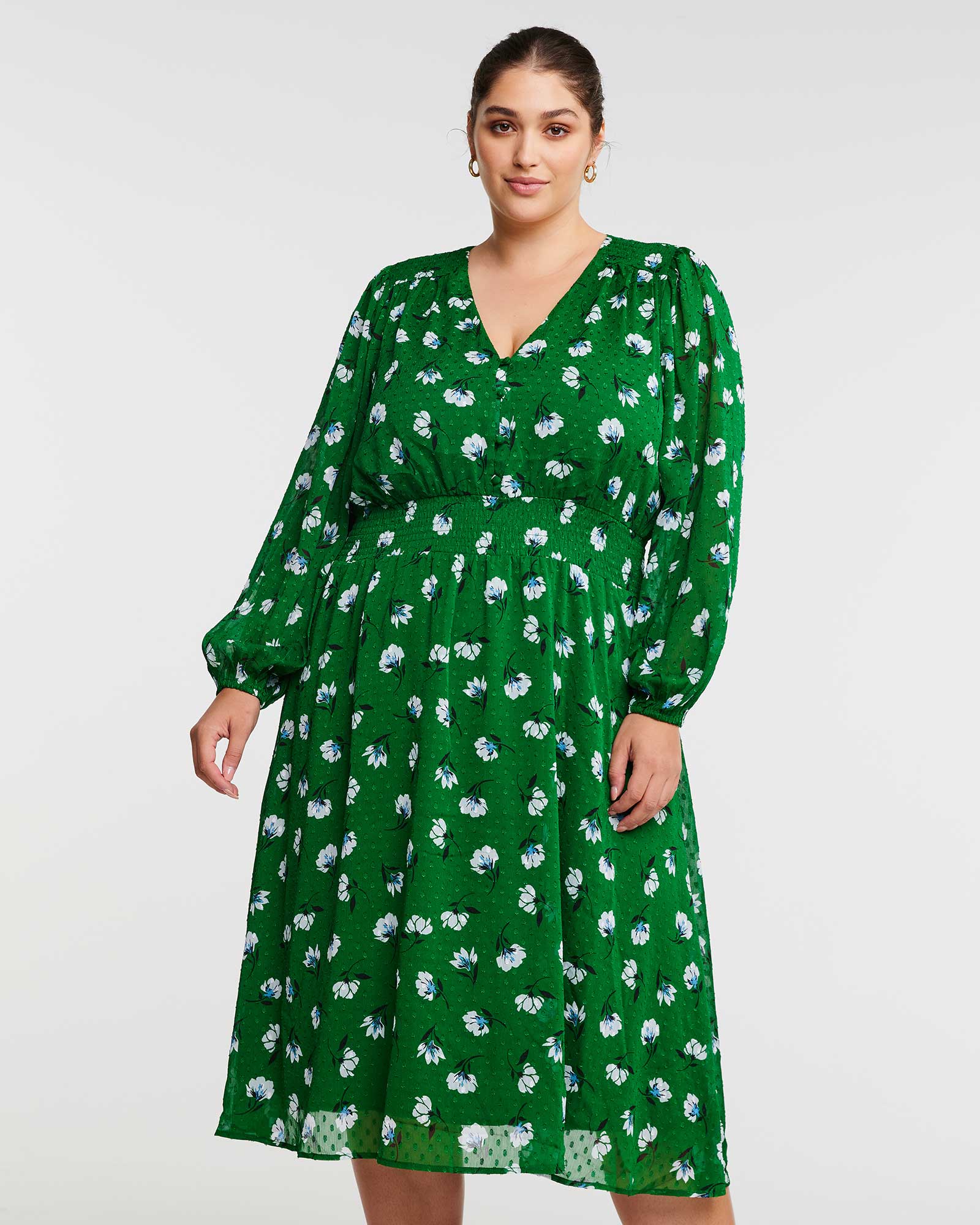 A woman wearing the Estelle Wispy Green Floral Long Sleeve Midi Dress.