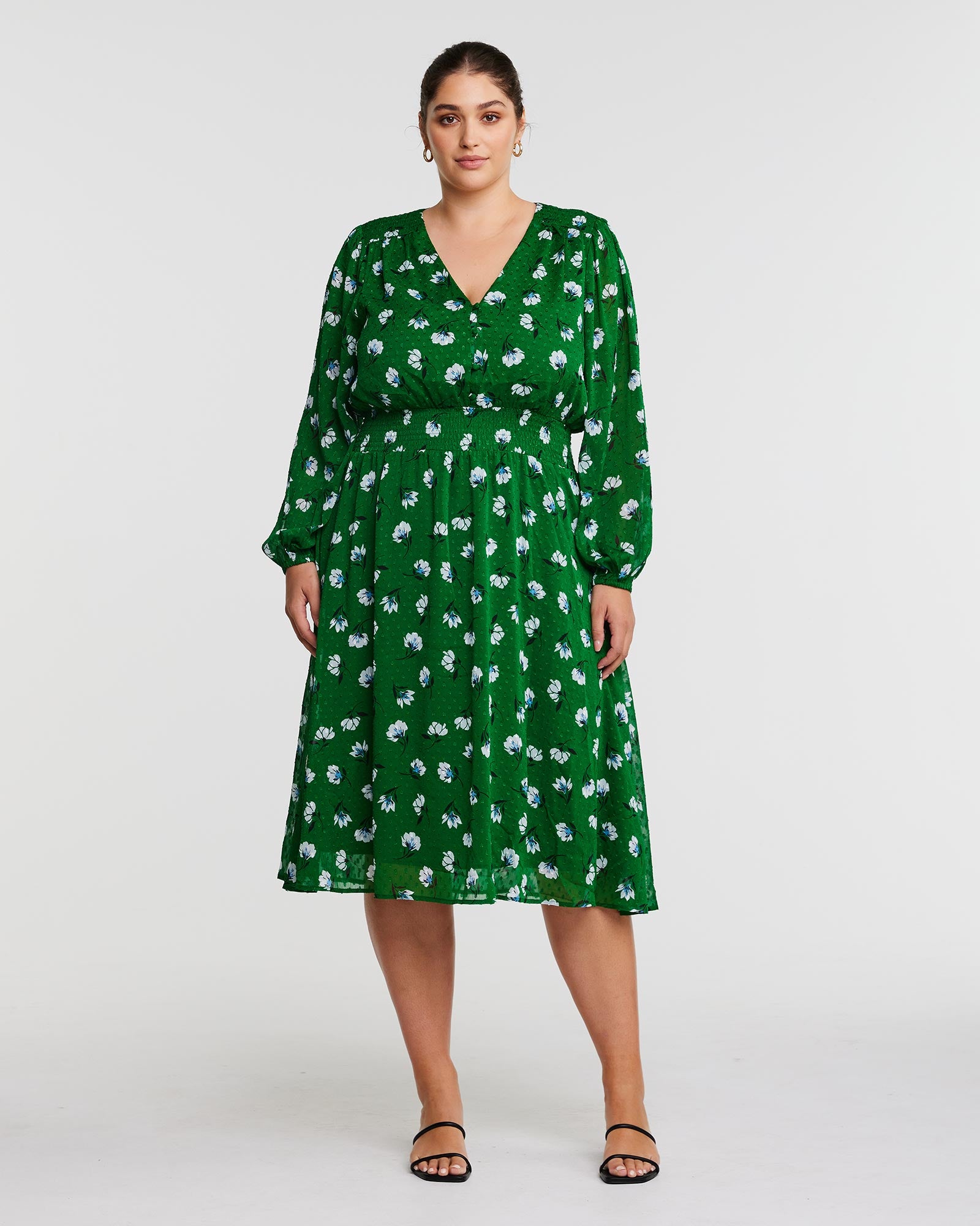 A woman wearing the Estelle Wispy Green Floral Long Sleeve Midi Dress.