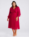 A plus size woman wearing a Estelle Raspberry Pleated Midi Dress.