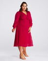 A plus size woman wearing a Estelle Raspberry Pleated Midi Dress.