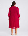 The back view of a plus size woman wearing a Estelle Raspberry Pleated Midi Dress.