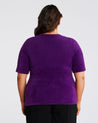 The back view of a woman wearing Estelle's Nora Fuzzy Purple Short-Sleeved Sweater.