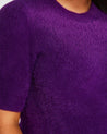 A close up of a woman wearing an Estelle Nora Fuzzy Purple Short-Sleeved Sweater.