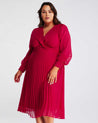 A plus size woman wearing a Estelle Raspberry Pleated Midi Dress.