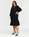 A plus size woman wearing the Elissa Dress with gold hardware detailing.