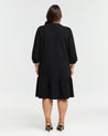 The back view of a woman wearing the Elissa Dress, a versatile black mini dress.