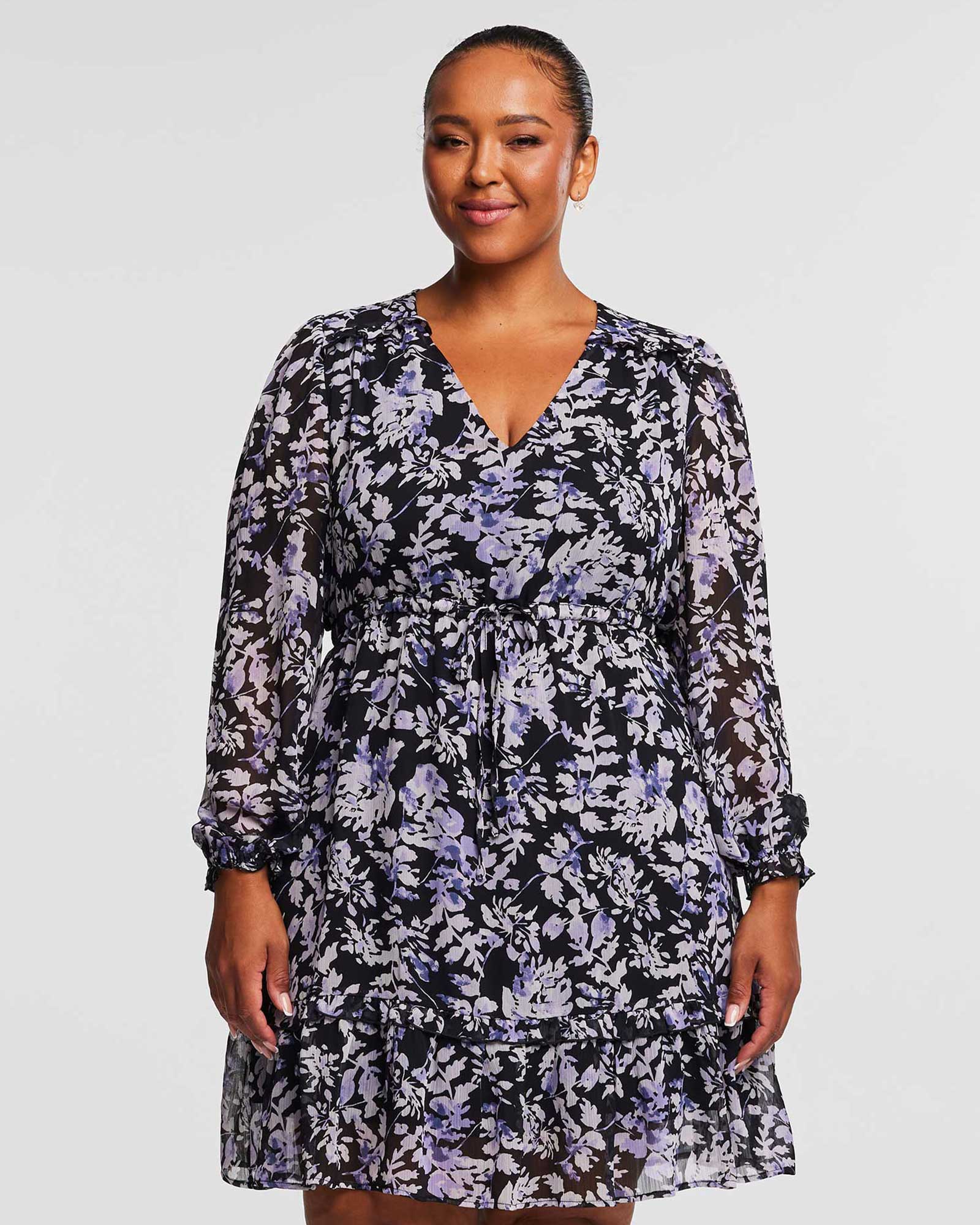 A plus size woman wearing a Estelle Wild Orchid Long Sleeved Floral Dress.