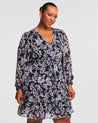 A plus size woman wearing a Estelle Wild Orchid Long Sleeved Floral Dress.