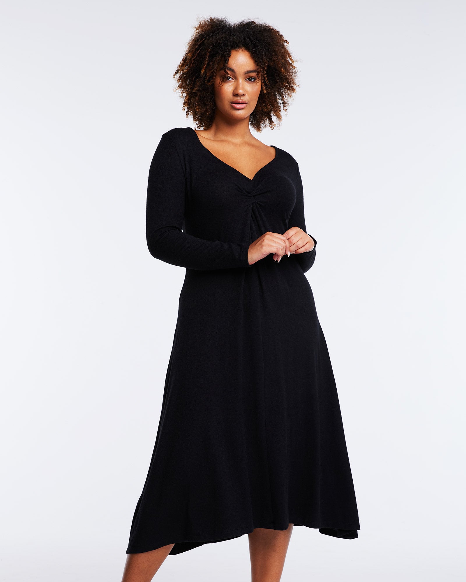 A versatile plus-sized woman wearing a Florentine Black Long Sleeve Midi Knit Dress.