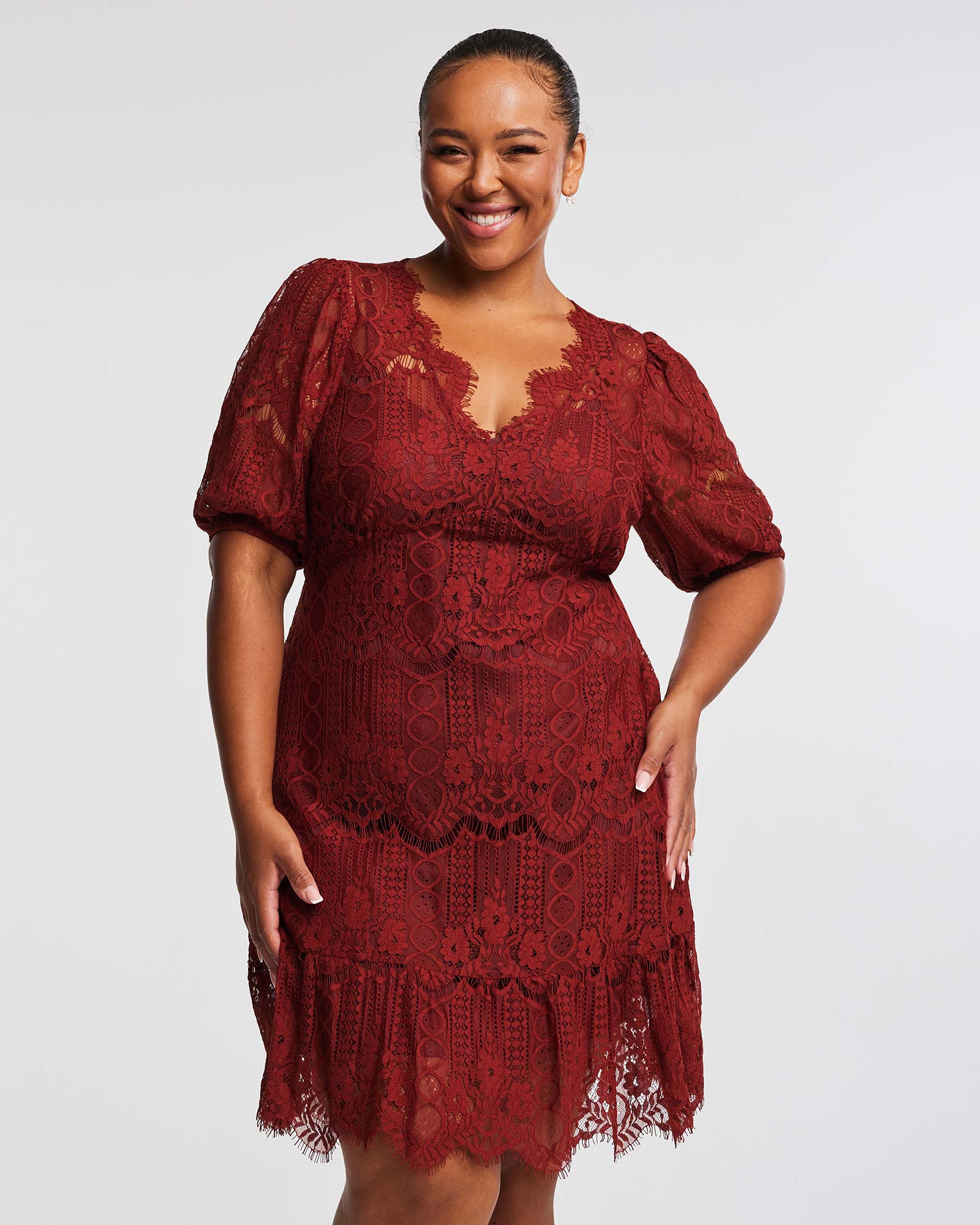 A plus-sized woman exuding elegance in a burgundy lace Liana Ginger Lace Mini Dress.