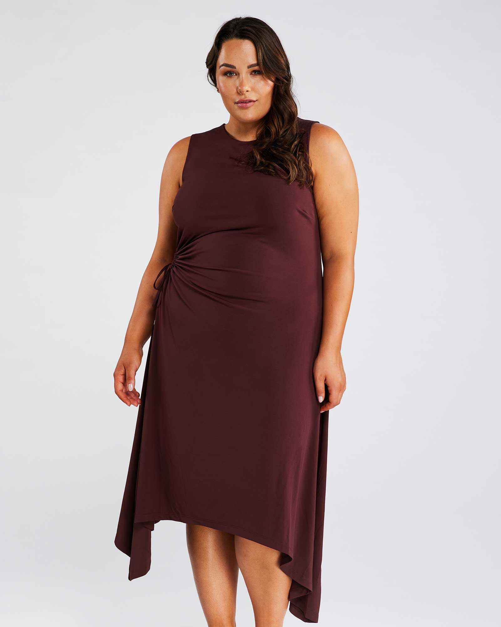 A plus size woman wearing the Estelle-us Yvette Dress in burgundy.