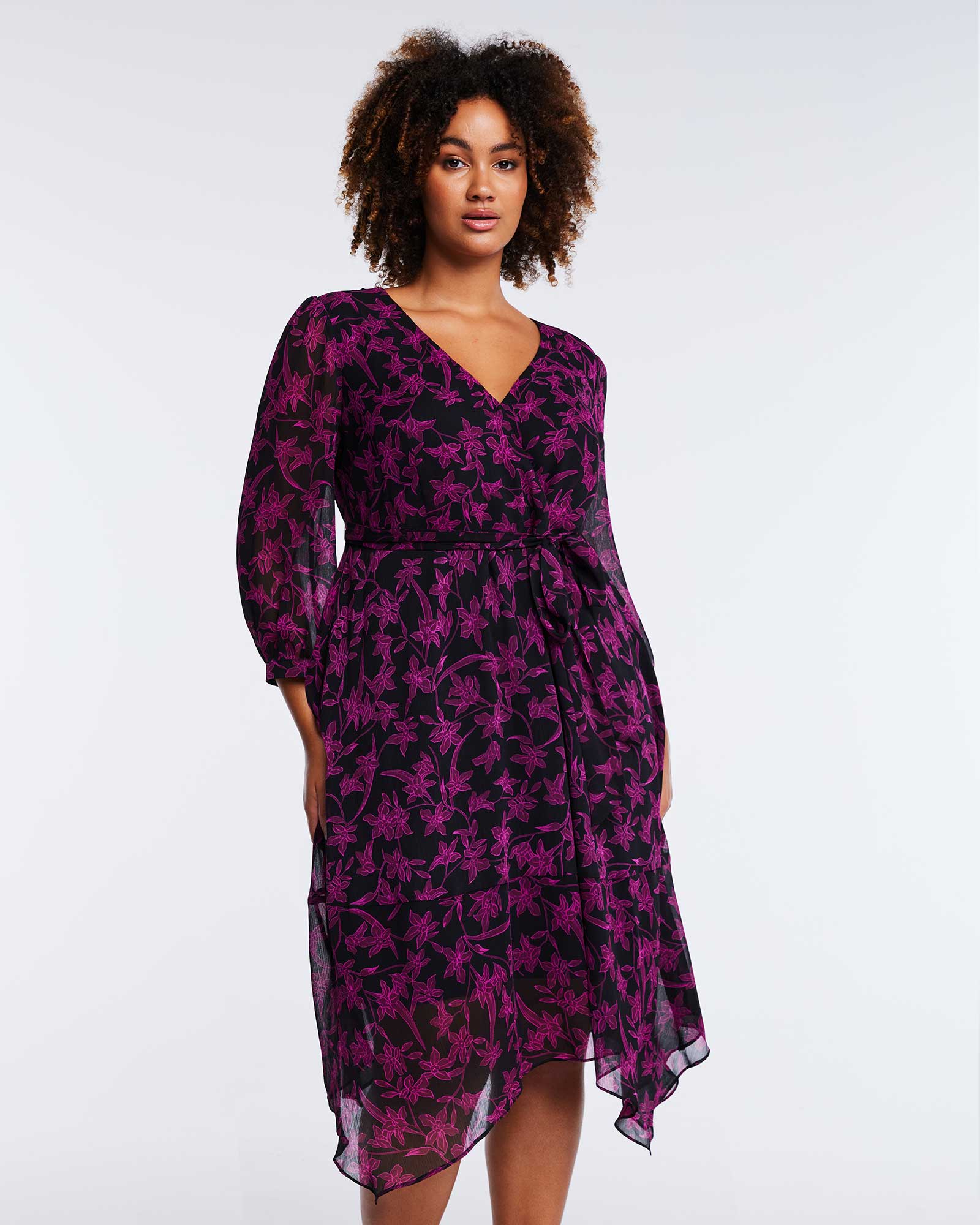 A comfortable and elegant plus size woman wearing a Boysenberry Bloom Black Pink Floral Midi Dress in purple and black.