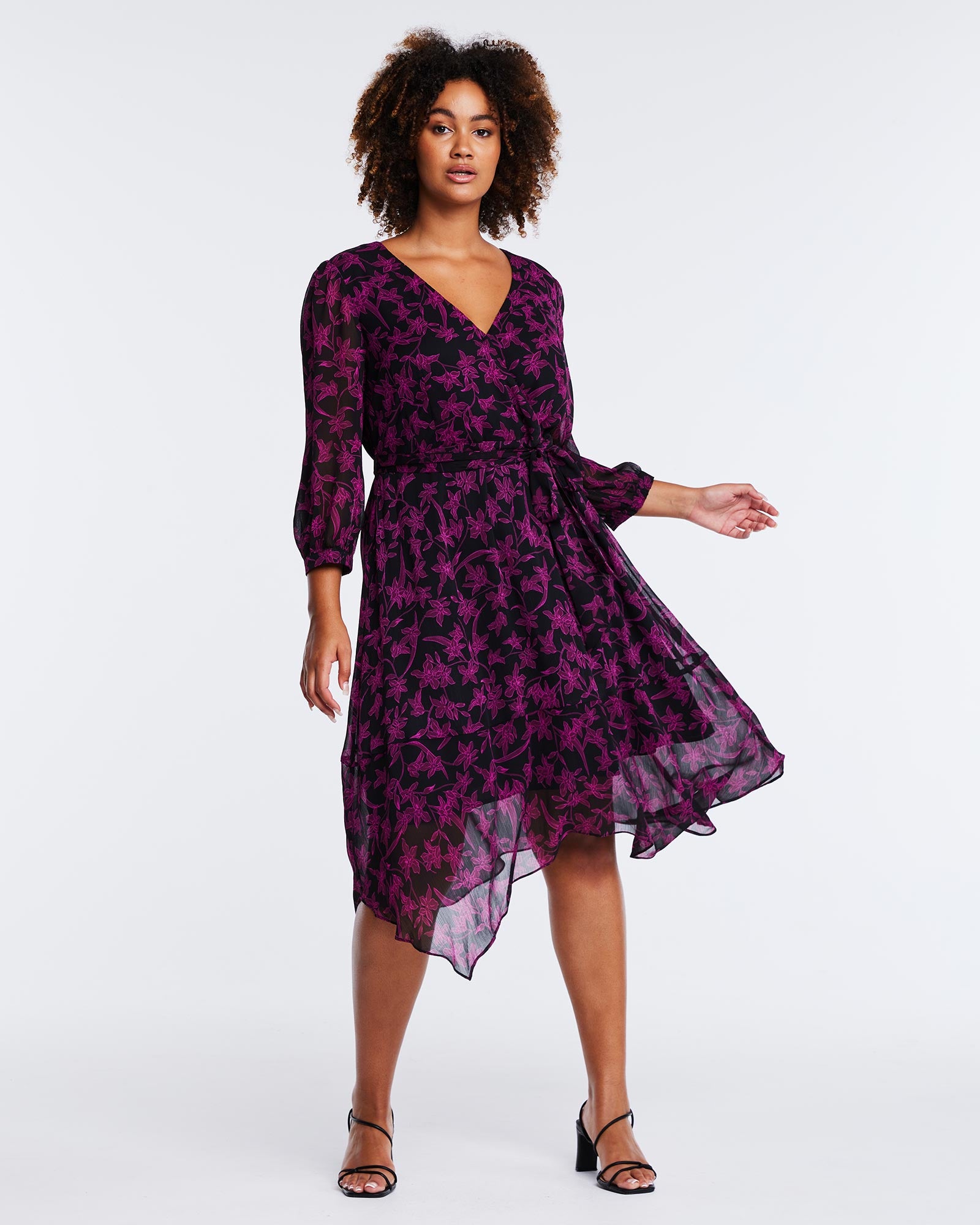 The model is wearing a comfortable and elegant Boysenberry Bloom Black Pink Floral midi dress with a v-neck.